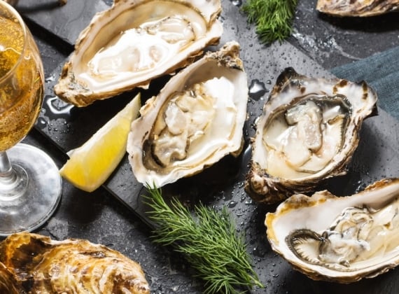 A plate of fresh oysters accompanies by a glass of wine.