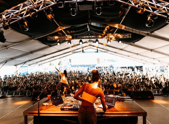A woman DJs to a large, excited crowd.