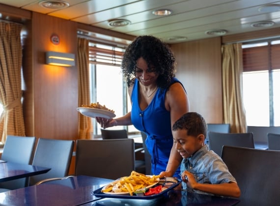 A mother puts down a plate of french fries for her son