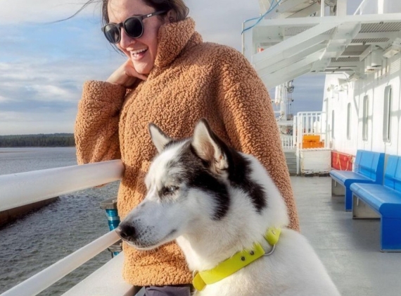 A woman and her husky look out over the side of the ferry