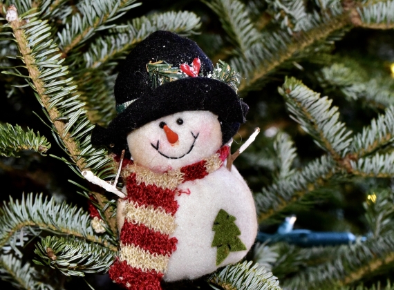 Jolly snowman ornament in a striped scarf and black felt hat. - stock photo