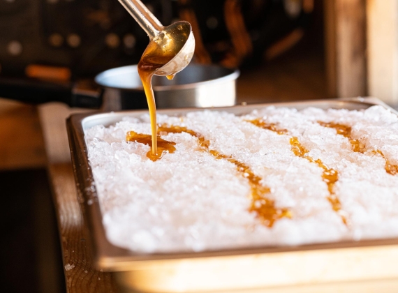 Maple syrup being ladled onto snow.