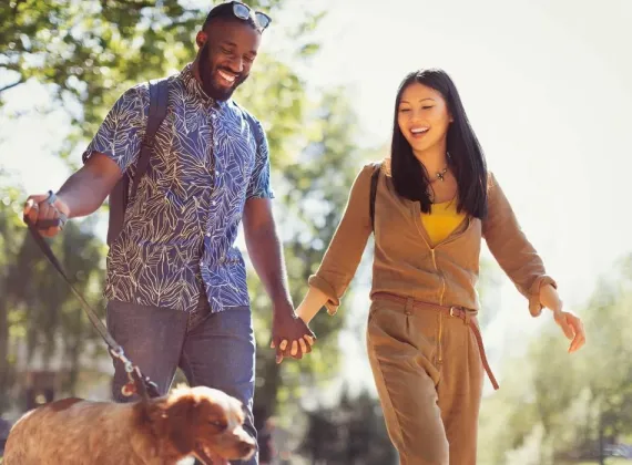 Two people walk their dog through the park