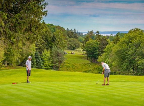 Two golf players putt the green at Digby Pines