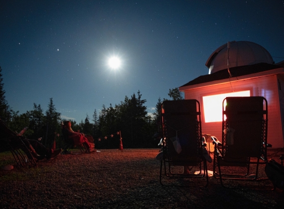 People on lawnchairs, observing the night sky in view of the Deep Sky Eye Observatory