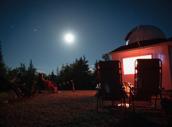 A person sitting outside of a cabin looking at the stars.