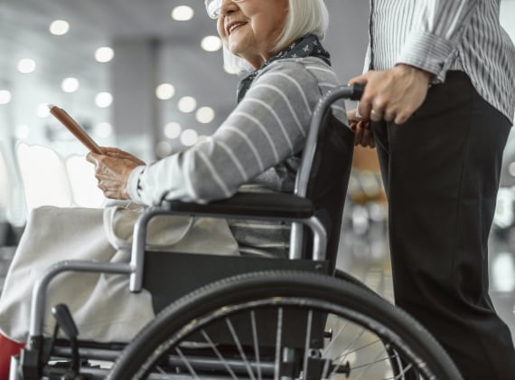 A person pushing an old woman in a wheelchair