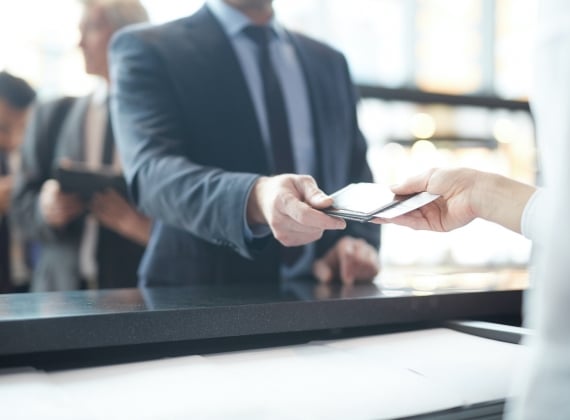 A person in a suit receives a ticket at a front desk