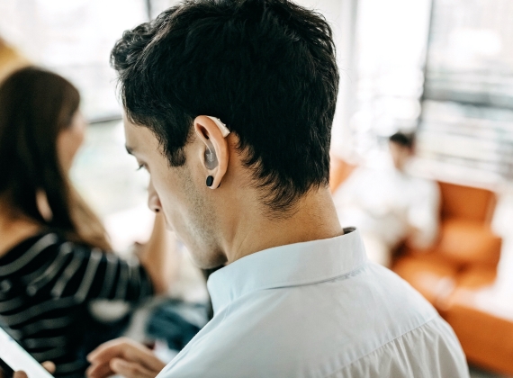 A person wearing a hearing aid checks their phone