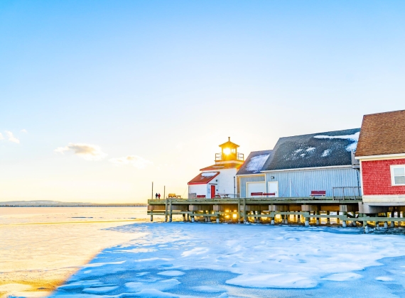 Colourful buildings on a wharf, frozen harbour in front of a sunrise