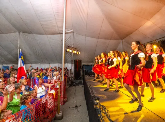 A crowd watches a group of girls dancing traditionally on stage.