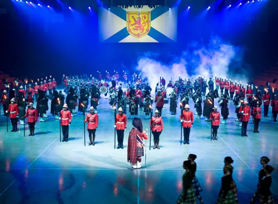 A group of costumed actors stand beneath a Nova Scotian flag.