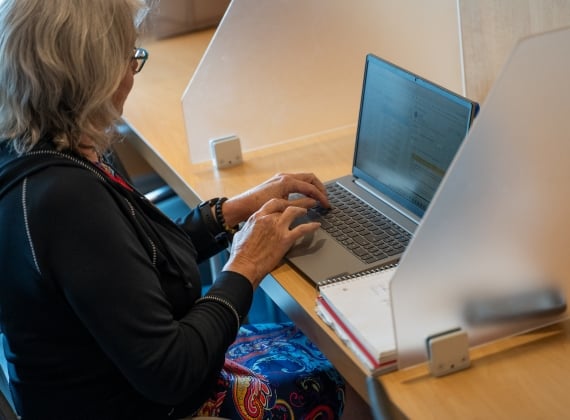 A woman uses a laptop at a work kiosk