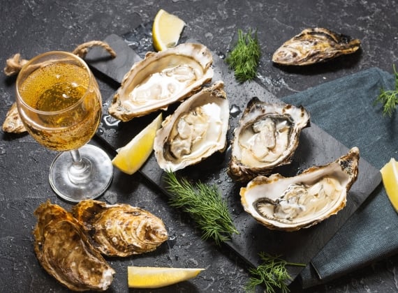 A plate of fresh oysters accompanies by a glass of wine