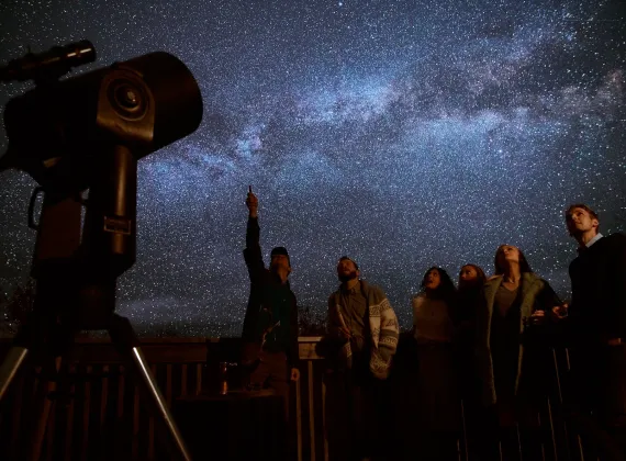 A group of people observing the milky way at an observatory site.